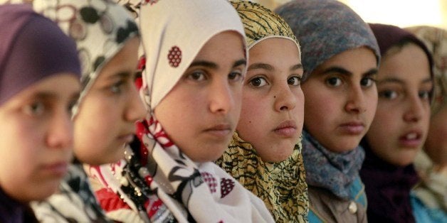 Syrian refugee girls sit at the United Nations Children's Fund (UNICEF) 'Child Friendly Spaces' (CFSs) in the Zaatari refugee camp, near the Jordanian border with Syria, on March 8, 2014. The CFSs used as temporary supports that contribute to the care and protection of children in emergencies, responding to childrens rights to protection, psychosocial well-being, and non-formal education. Jordan is home to more than 500,000 Syrian refugees. AFP PHOTO / KHALIL MAZRAAWI (Photo credit should read KHALIL MAZRAAWI/AFP/Getty Images)