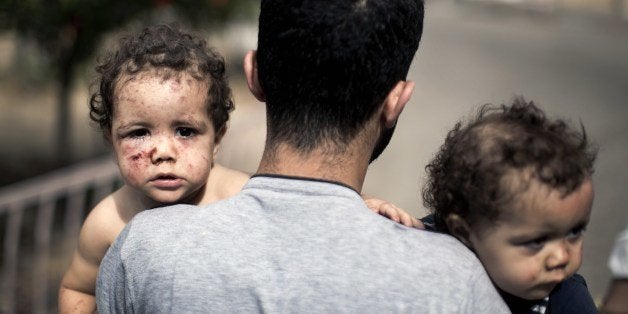 A Palestinian man holds his daughters, Shada and Lama al-Ejla, who were injured in an Israeli tank attack, as he leaves al-Sh