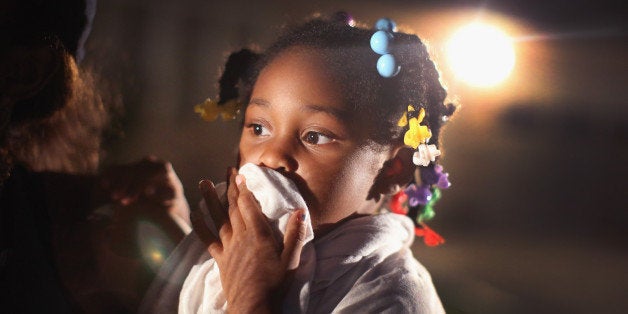 FERGUSON, MO - AUGUST 11: A child uses a rag to shield her face from tear gas being fired by police who used it to force pro