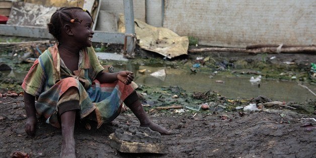 A young girl smiles on August 1, 2014 as she plays next to flooded housing in the UN Protection of Civilians (PoC) site in Up