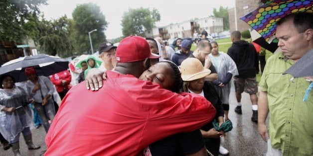 Two people embrace on August 16, 2014, at the location where 18-year-old Michael Brown was killed on Canfield Drive in Ferguson, Missouri. Vandals attacked stores in Ferguson early August 9, hours after police said the unarmed black teenager was a robbery suspect. The allegation reignited anger in the town, a St. Louis suburb in the state of Missouri, that has endured on-and-off rioting since Brown was killed on August 9. AFP PHOTO/Joshua LOTT (Photo credit should read Joshua LOTT/AFP/Getty Images)