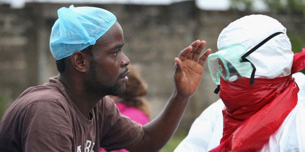 MONROVIA, LIBERIA - AUGUST 17: A Liberian burial team carefully puts on protective clothing before retrieving the body of an Ebola victim from his home on August 17, 2014 near Monrovia, Liberia. The epidemic has killed more than 1,000 people in four African countries, and Liberia now has had more deaths than any other country. (Photo by John Moore/Getty Images)