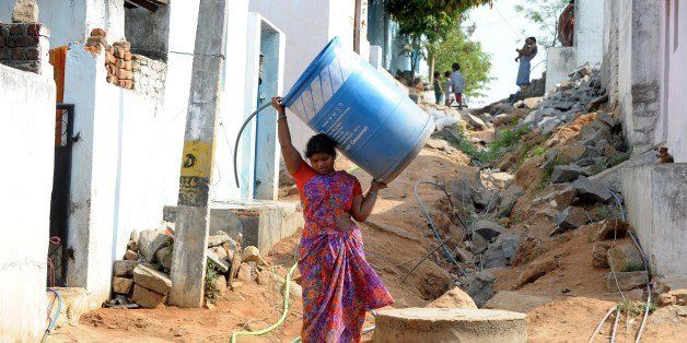 An Indian woman carries an empty container as residents use motors to pump potable drinking water from a government water supply pipe line on the outskirts of Hyderabad on April 3, 2014. Water shortages are a problem in the southern Indian city as summer temperatures soar above the 40 degrees Celsius. AFP PHOTO / Noah SEELAM (Photo credit should read NOAH SEELAM/AFP/Getty Images)