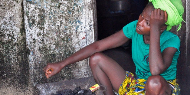 In this photo taken on Wednesday, Aug. 27, 2014, a woman sits next to her home with coals packed on her fire place, in the West Point area that has been hit hard by the Ebola virus, with residents not allowed to leave West Point, as government forces clamp down on movement to prevent the spread of Ebola, in Monrovia, Liberia. The Ebola outbreak in West Africa eventually could exceed 20,000 cases, more than six times as many as are now known, the World Health Organization said Thursday. A new plan released by the U.N. health agency to stop Ebola also assumes that the actual number of cases in many hard-hit areas may be two to four times higher than currently reported.( AP Photo/Abbas Dulleh)