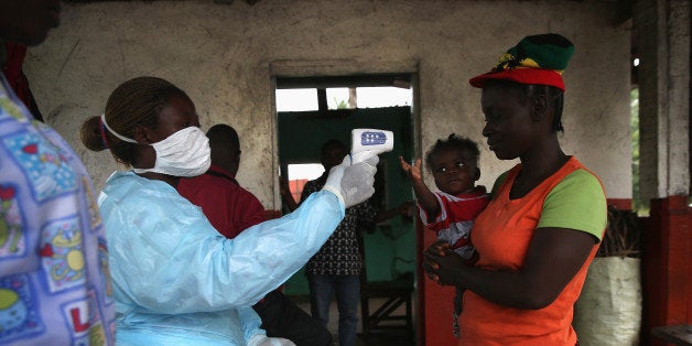 DOLO TOWN, LIBERIA - AUGUST 24: A Liberian Ministry of Health worker checks people for Ebola symptoms at a checkpoint near t