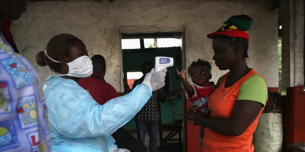 DOLO TOWN, LIBERIA - AUGUST 24: A Liberian Ministry of Health worker checks people for Ebola symptoms at a checkpoint near the international airport on August 24, 2014 near Dolo Town, Liberia. The government has been slow to deliver sufficient food aid to the town of some 15,000 people, following an August 20 quarantine to stop the Ebola epidemic from spreading from the community of some 15,000 people, located near Liberia's international airport. The military is stopping residents from leaving the area. Local Ministry of Health personnel say they have sent 20 sick people in the previous days to the Doctors Without Borders (MSF), treatment center for to be tested for Ebola. (Photo by John Moore/Getty Images)