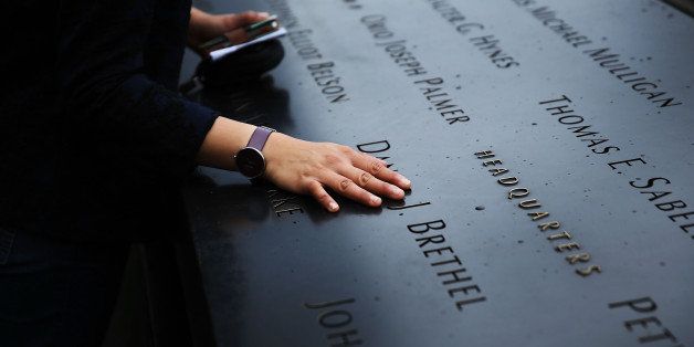 NEW YORK, NY - MAY 15: A woman places a hand on the names engraved along the South reflecting pool at the Ground Zero memorial site during the dedication ceremony of the National September 11 Memorial Museum in New York May 15, 2014 in New York City. The museum spans seven stories, mostly underground, and contains artifacts from the attack on the World Trade Center Towers on September 11, 2001 that include the 80 ft high tridents, the so-called 'Ground Zero Cross,' the destroyed remains of Company 21's New York Fire Department Engine as well as smaller items such as letter that fell from a hijacked plane and posters of missing loved ones projected onto the wall of the museum. The museum will open to the public on May 21. (Photo by Spencer Platt/Getty Images)