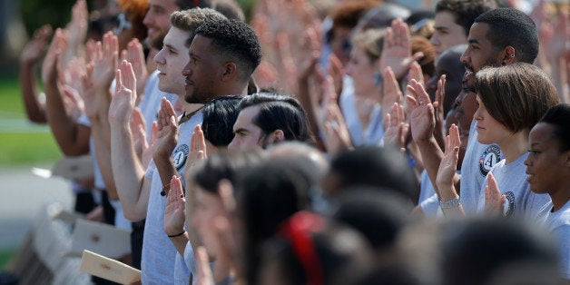 AmeriCorps volunteers take a pledge as President Barack Obama and former President Bill Clinton mark the 20th anniversary of AmeriCorps, which promotes volunteerism and community service, on the South Lawn at the White House in Washington, Friday, Sept. 12, 2014. (AP Photo/Charles Dharapak)