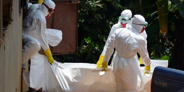 Liberian Red Cross health workers wearing protective suits carry the body of a 18-months baby victim of the Ebola virus on Se