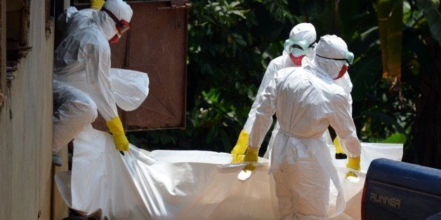 Liberian Red Cross health workers wearing protective suits carry the body of a 18-months baby victim of the Ebola virus on September 12, 2014 in a district of Monrovia. Liberia has been hit hard by the Ebola epidemic, the worst in history, which has killed more than 2,400 people since it erupted earlier this year, according to World Health Organization. AFP PHOTO / ZOOM DOSSO (Photo credit should read ZOOM DOSSO/AFP/Getty Images)