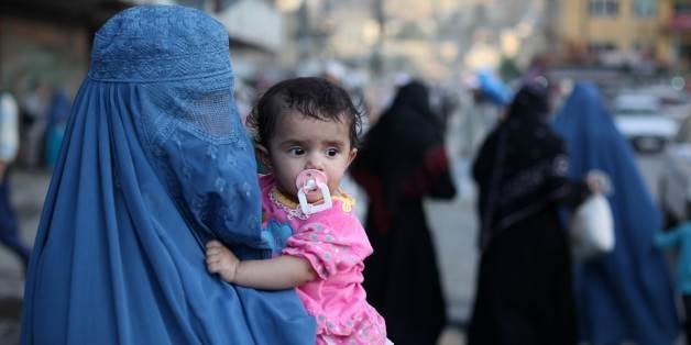 A woman wearing a burqa carries a child through the old town area of Kabul on June 19, 2010. At least five civilians, including two young girls, were killed in an air strike by NATO forces in eastern Afghanistan, police and hospital officials said. AFP PHOTO / ED JONES (Photo credit should read Ed Jones/AFP/Getty Images)