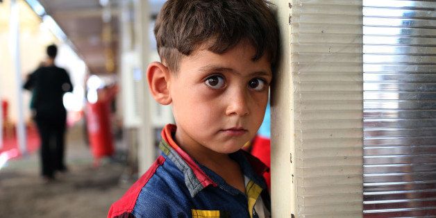 A displaced Iraqi Christian boy who fled with his parents from the Christian village of Hamdania near Mosul province in Iraq, looks on at a temporary shelter for the displaced Christian families in Ainkawa, a suburb of Irbil, with a majority Christian population, Iraq, Saturday, June 28, 2014. Around 2,000 Christians had entered the Kurdish city of Irbil by Thursday morning, June 26. A Christian official there said the Kurdish region is the only part of Iraq where Christians are protected from violence. (AP Photo/Hussein Malla)