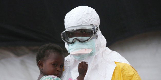 PAYNESVILLE, LIBERIA - OCTOBER 05: A Doctors Without Borders (MSF), health worker in protective clothing holds a child suspe