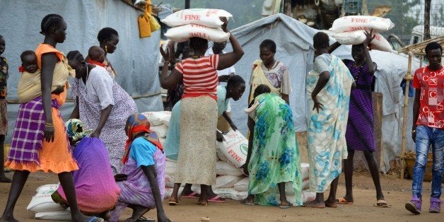 Women carry maize flour sacks during a food distribution by the Catholic Church to refugees and displaced people in Juba on August 30, 2014. War-torn South Sudan faces possible famine early next year, the UN chief in the country warned on August 28, as aid workers said the shooting down of a UN helicopter threatened efforts to save lives. Famine implies that at least 20 percent of households face extreme food shortages, there is acute malnutrition in over 30 percent of people, and two deaths per 10,000 people every day, according to the UN's definition. AFP PHOTO / SAMIR BOL (Photo credit should read SAMIR BOL/AFP/Getty Images)