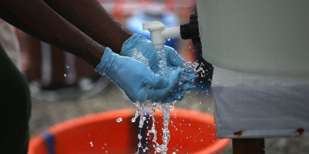 MONROVIA, LIBERIA - OCTOBER 05: A health worker washes his hands in chlorinated water while removing protective clothing after an hourlong shift in the high risk area of the Doctors Without Borders (MSF), treatment center on October 5, 2014 in Paynesville, Liberia. To reduce potentially deadly mistakes due to the heat while wearing protective clothing, MSF staff rotate out of the high risk areas each hour. The epidemic has killed more than 3,400 people in West Africa, according to the World Health Organization. (Photo by John Moore/Getty Images)