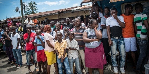 MONROVIA, LIBERIA - OCTOBER 15: People crowd watch Red Cross members as they carry dead body of Mambodou Aliyu (35) died due to the Ebola virus, in Monrovia, Liberia on 15 October, 2014. (Photo by Mohammed Elshamy/Anadolu Agency/Getty Images)