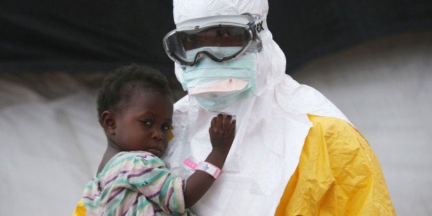 PAYNESVILLE, LIBERIA - OCTOBER 05: A Doctors Without Borders (MSF), health worker in protective clothing holds a child suspected of having Ebola in the MSF treatment center on October 5, 2014 in Paynesville, Liberia. The girl and her mother, showing symptoms of the deadly disease, were awaiting test results for the virus. The Ebola epidemic has killed more than 3,400 people in West Africa, according to the World Health Organization. (Photo by John Moore/Getty Images)