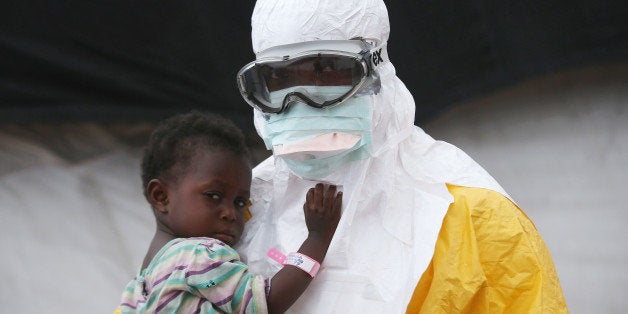 PAYNESVILLE, LIBERIA - OCTOBER 05: A Doctors Without Borders (MSF), health worker in protective clothing holds a child suspected of having Ebola in the MSF treatment center on October 5, 2014 in Paynesville, Liberia. The girl and her mother, showing symptoms of the deadly disease, were awaiting test results for the virus. The Ebola epidemic has killed more than 3,400 people in West Africa, according to the World Health Organization. (Photo by John Moore/Getty Images)