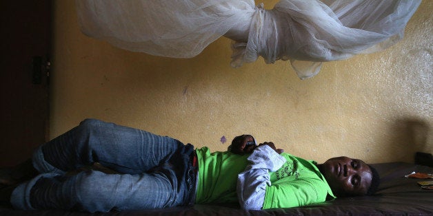 DOLO TOWN, LIBERIA - AUGUST 24: John Karpee, 24, lies in an observation room at a government clinic on August 24, 2014 in Do