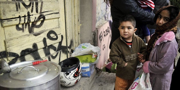 Immigrant children wait for food donated by activists from a soup kitchen, in a poor neighborhood in Athens, on February 6, 2