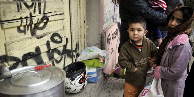 Immigrant children wait for food donated by activists from a soup kitchen, in a poor neighborhood in Athens, on February 6, 2012. Greece today began constructing a fence on its border with Turkey to keep out thousands of undocumented migrants and refugees seeking to cross into Europe, the country's police minister said. AFP PHOTO/ LOUISA GOULIAMAKI (Photo credit should read LOUISA GOULIAMAKI/AFP/Getty Images)