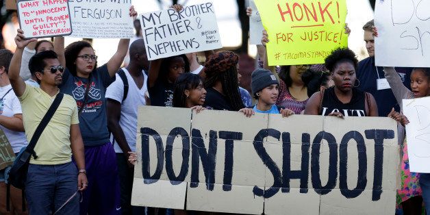Protesters hold a sign that reads "Don't Shoot" as they attend an evening rally Tuesday, Aug. 19, 2014, in Tacoma, Wash. Several hundred people attended the peaceful gathering to show support for protesters in Ferguson, Missouri, where the fatal shooting of 18-year-old Michael Brown has sparked nightly clashes between protesters and police. (AP Photo/Ted S. Warren)
