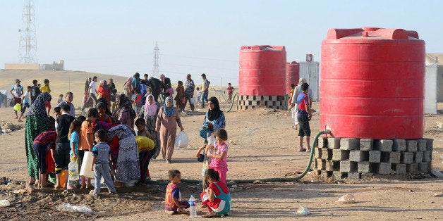 ARBIL, IRAQ - JULY 23: Woman refugees draw water from draw well in refugee camp in Arbil, Iraq on 23 July, 2014. Iraqi people fled from the attacks of army groups led by Islamic state in Iraq and Syria and stay in a tent camp and women refugees undertake the all responsibilities like cooking, washing, cleaning. (Photo by Dilek Mermer/Anadolu Agency/Getty Images)