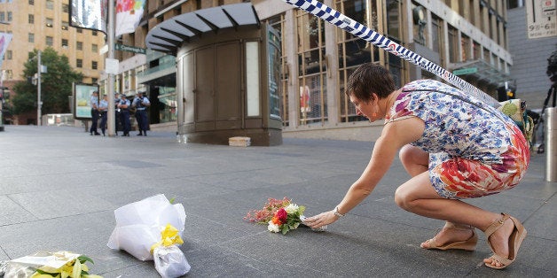 SYDNEY, AUSTRALIA - DECEMBER 16: A woman cries as she leaves flowers to pay her respects at Martin Place on December 16, 201