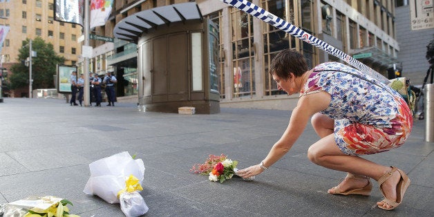 SYDNEY, AUSTRALIA - DECEMBER 16: A woman cries as she leaves flowers to pay her respects at Martin Place on December 16, 2014 in Sydney, Australia. The siege in Sydney's Lindt Cafe in Martin Place is over after 16 hours. Police raided the cafe just after 2am AEDT on Tuesday morning. Three people have been confirmed killed, two hostages and the gunman. (Photo by Mark Metcalfe/Getty Images)