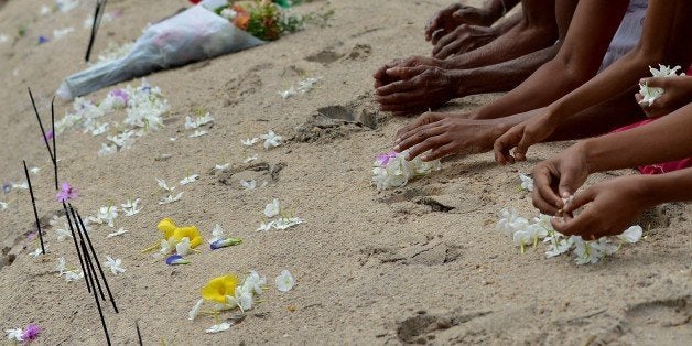 Sri Lankan women commemorate the victims of the December 2004 tsunami, offering flowers, prayers and alms during a special ceremony to mark the tenth anniversary, in the southern coastal town of Peraliya on December 26, 2014, the tenth anniversary of the deadly Asian tsunami. The Ocean Queen Express, which was rebuilt after the tsunami, has become a symbol of the disaster in Sri Lanka and was at the centre of commemorations for the country's 31,000 victims. Survivors and relatives of the dead boarded the train December 26 morning in Colombo and headed to Peraliya, the exact spot where it was ripped from the tracks, around 90 kilometres (56 miles) south of Colombo. AFP PHOTO / ISHARA S. KODIKARA (Photo credit should read Ishara S.KODIKARA/AFP/Getty Images)