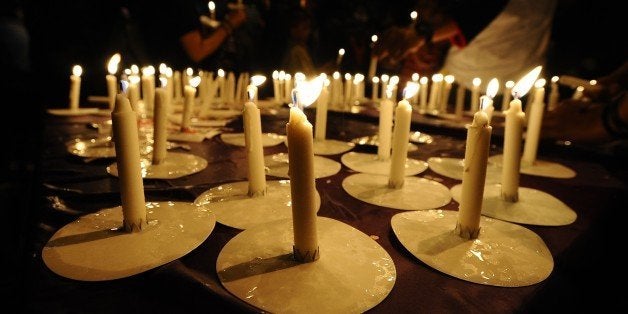 SURABAYA, INDONESIA - DECEMBER 31: Indonesians light candles during a prayer for victims of the AirAsia flight QZ8501 crash on December 31, 2014 in Surabaya, Indonesia. A massive recovery operation has begun following confirmation from Indonesian officials that remains and debris found in waters off Borneo are from the missing AirAsia plane. Flight QZ8501 from Surabaya to Singapore, with 162 people on board, lost contact with air traffic control at 07:24 a.m. local time on December 28. (Photo by Robertus Pudyanto/Getty Images)