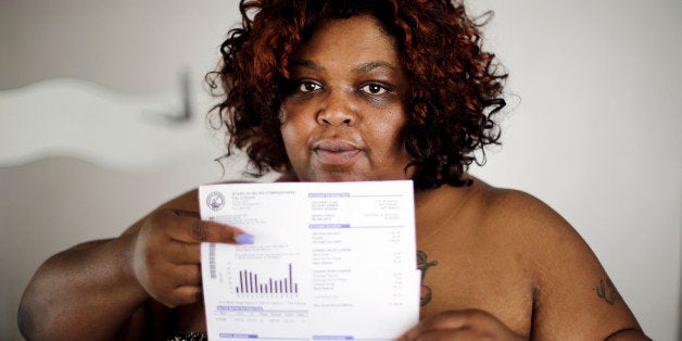 Nicole Hill holds up her past due water bill at her home in Detroit Wednesday, June 25, 2014. Detroit Water department spokeswoman Curtrise Garner says service to 4,500 customers was cut last month, but more than half then paid up. Garner says about $90 million is owed by 90,000 active customers who are behind at least two months. United Nations experts say water shutoffs at Detroit homes due to overdue bills violate international human rights. (AP Photo/Paul Sancya)