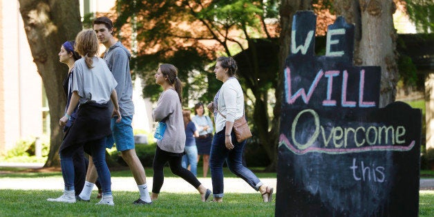 People walk past a sign on the Seattle Pacific University campus that reads "We Will Overcome This," Friday, June 6, 2014 in Seattle, the day after a shooting took place at Otto Miller Hall at the school. A 19-year-old man was fatally shot and two other young people were wounded after a gunman entered the foyer and started shooting. Aaron R. Ybarra, 26, was booked into the King County Jail late Thursday for investigation of homicide, according to police and the jail roster. (AP Photo/Ted S. Warren)