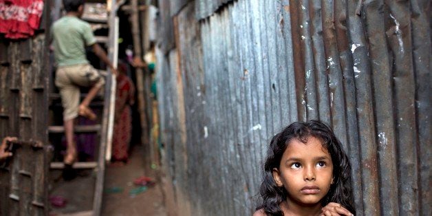 A Bangladeshi child stands in an alley as a boy climbs a ladder outside their home at a slum in Dhaka, Bangladesh, Friday, Oct. 17, 2014. The International Day for the Eradication of Poverty is observed on October 17 and is designated to promote awareness of the need to eradicate poverty and destitution in all countries. (AP Photo/A.M. Ahad)