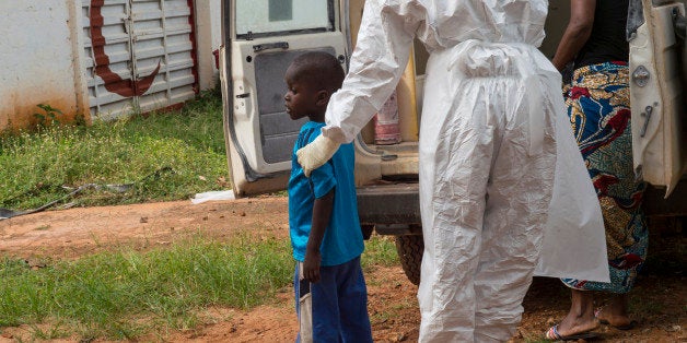 FREETOWN, SIERRA LEONE NOVEMBER 16: Mamie Kuyateh helps a 4-year-old boy off an ambulance at a holding center in in Freeto
