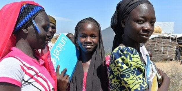 Girls carry thier school books on November 13, 2014 in a UNHCR camp for Nigerian refugees in Minawao, in the extreme north-west of Cameroon. Almost 17,000 Nigerians in this camp have fled their country , terrified of raids by the Islamists of Boko Haram..AFP PHOTO: Reinnier Kazé (Photo credit should read Reinnier KAZE/AFP/Getty Images)
