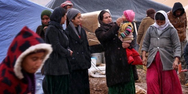 Displaced Iraqi women from the Yazidi community, who fled violence between Islamic State (IS) group jihadists and Peshmerga fighters in the northern Iraqi town of Sinjar, gather around their tents at a refugee camp set up on Mount Sinjar on January 15, 2015. IS group has targeted Yazidis and other minorities in northern Iraq in a campaign that rights group Amnesty International said in a report amounted to ethnic cleansing, murdering civilians and enslaving others for a fate that some captives consider worse than death. IS militants have overrun swathes of Iraq since June 2014, declared a cross-border caliphate also encompassing parts of neighbouring Syria and carried out a litany of abuses in both countries. AFP PHOTO / SAFIN HAMED (Photo credit should read SAFIN HAMED/AFP/Getty Images)