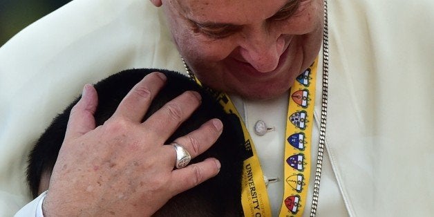 Pope Francis embraces a child during his visit to the University of Santo Tomas in Manila on January 18, 2015. Pope Francis will celebrate mass with millions in the Philippine capital on January 18 in what could be the world's biggest papal gathering, capping off a dramatic trip in the Catholic Church's Asian heartland. AFP PHOTO / GIUSEPPE CACACE (Photo credit should read GIUSEPPE CACACE/AFP/Getty Images)