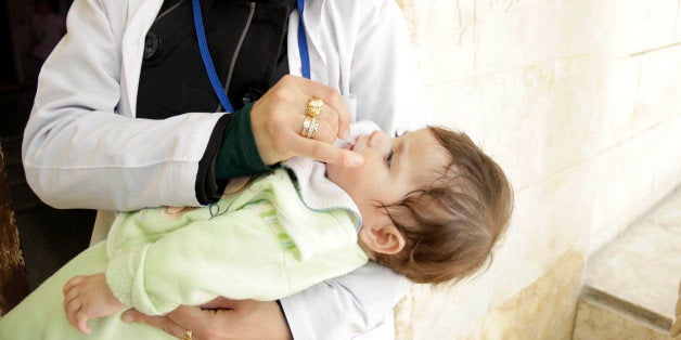 ALEPPO, SYRIA - MAY 5: A health worker gives polio vaccine drops to a Syrian child during the polio vaccination campaign organized by Syrian National Coalitions Assistance Coordination Unit (ACU), Turkey's Health Ministry and Turkish Red Crescent on May 05, 2014 in Aleppo, Syria. (Photo by ACU/Anadolu Agency/Getty Images)