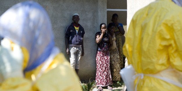 People react as Guinean Red Cross workers arrive to remove the corpse of a neighbour who died of Ebola in Macenta on November