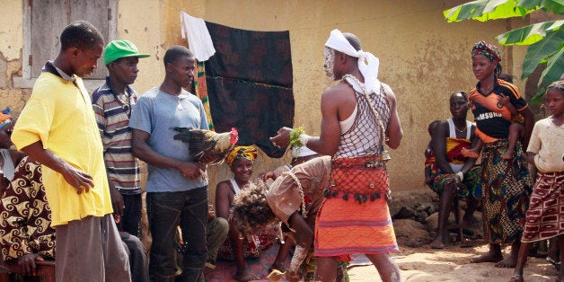 In this photo taken on Feb. 23, 2015, traditional healers, center, take part in a exorcism as villagers hand them a chicken, in Meliandou, Guinea. Here at ground zero of West Africaâs Ebola outbreak, a local traditional healer returned to complete the removal of a curse residents believe could have been placed on their village in Guinea. (AP Photo/Youssouf Bah)