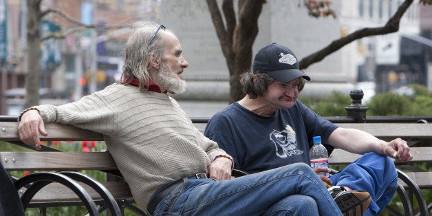 New York, NY. A pair of homeless men sit and pass the time on a park bench in lower Manhattan.