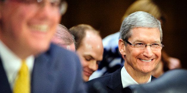 Tim Cook, chief executive officer of Apple Inc., right, smiles as J. Richard Harvey, professor of practice at the Villanova University School of Law and Graduate Tax Program and former Internal Revenue Service (IRS) senior advisor, testifies at a Senate Permanent Subcommittee on Investigations hearing in Washington, D.C., U.S., on Tuesday, May 21, 2013. Cook defended his companyâs use of offshore tax shelters before U.S. senators who castigated the most-valuable technology company for avoiding $9 billion and more in payments. Photographer: Pete Marovich/Bloomberg via Getty Images 