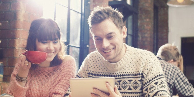 Couple using tablet computer in cafe