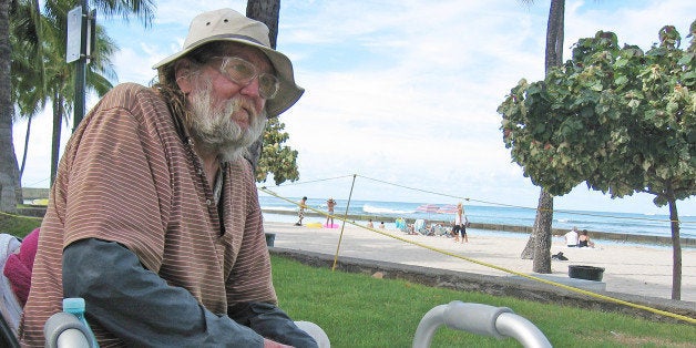 In this photo taken Monday Sept. 8, 2014, Jim Trevarthen, 62, watches the surfers near Waikiki Beach in Honolulu. Trevarthen is one of many homeless people who is unhappy with the city's proposals to ban sitting and lying down on sidewalks in the tourist mecca. Honolulu's city council is set to vote Wednesday on a sit-lie ban in Waikiki and Honolulu, aiming to keep homeless people out of sight after pressure from the tourism industry. (AP Photo/Cathy Bussewitz)