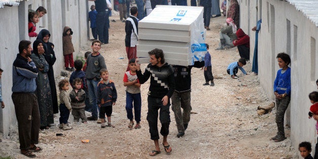 IDLIB, SYRIA - NOVEMBER 19: Members of Hayrat Humanitarian Aid Association distribute aids to Syrian families who were escaped from civil war and shelter in a small village set up by Hayrat Humanitarian Aid Association in Idlib, Syria, on November 19, 2014. (Photo by Ismail Hakk Demir/Anadolu Agency/Getty Images)