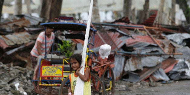 A typhoon survivor carries an oar and a life vest which were donated by the charitable organization Urban Poor Associates nearly three months after Typhoon Haiyan devastated Tacloban city and other provinces in central Philippines Thursday, Feb. 13, 2014. International and local agencies have been working to help rehabilitate typhoon-ravaged central Philippines since the typhoon struck Nov. 8, 2013 that left a wide swath of destruction. (AP Photo/Bullit Marquez)