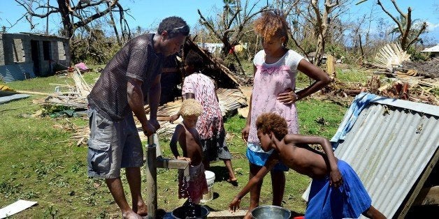 Locals pump water from the well in their coastal village amongst debris left in the aftermath of Cyclone Pam on the Vanuatu island of Tanna on March 18, 2015. Aid began arriving in some of cyclone-hit Vanuatu's worst affected islands on March 18 but others remain isolated, with flights over the Pacific nation showing desperate villagers spelling out the letter 'H' for help. AFP PHOTO / JEREMY PIPER (Photo credit should read JEREMY PIPER/AFP/Getty Images)