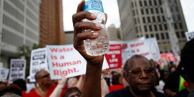 DETROIT, MI - JULY 18 : A man holds a bottle of water as he joins other demonstrators protesting against the Detroit Water and Sewer Department July 18, 2014 in Detroit, Michigan. The Detroit Water and Sewer Department have disconnected water to thousands of Detroit residents who are delinquent with their bills. (Photo by Joshua Lott/Getty Images)