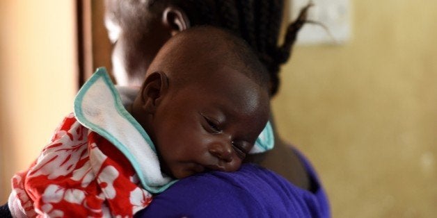 A baby naps on his mother's shoulder as they enter the vaccination room during a routine visit at the Kuntorloh Community Hea